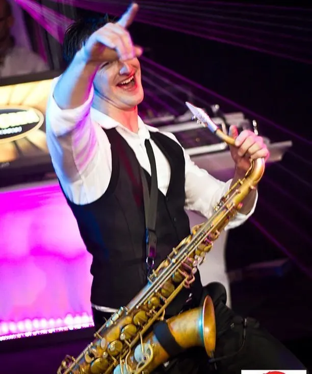 Saxophonist performing on stage at a holiday party
